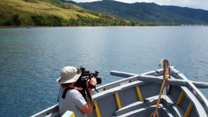 A man on a boat records his surroundings with a video camera.